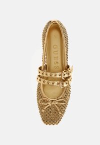 Goldfarbene flache Schuhe mit durchbrochenem Design, doppeltem Riemen mit runden Schnallen, Schleifendetail an der Spitze und Nietenakzenten entlang der Kanten.