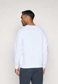 Hvit genser med rund hals og ribbestrikkede mansjetter. Laget av mykt stoff, med en glatt tekstur og avslappet passform.