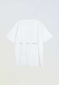 Biała koszulka z krótkim rękawem z czarnym napisem "Fiction Vision Phantasia" nadrukowanym w linii na środku pleców.