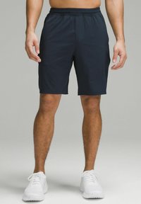 Men's navy athletic shorts with an elastic waistband, lightweight fabric, and a smooth texture, paired with white running shoes.