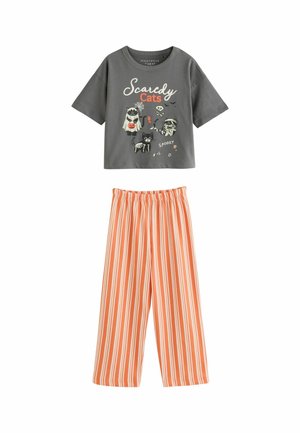 Graues Kurzarmshirt mit Halloween-Katzenmotiven und "Scaredy Cats" Text, kombiniert mit orange-weißen, vertikal gestreiften, weit geschnittenen Hosen.