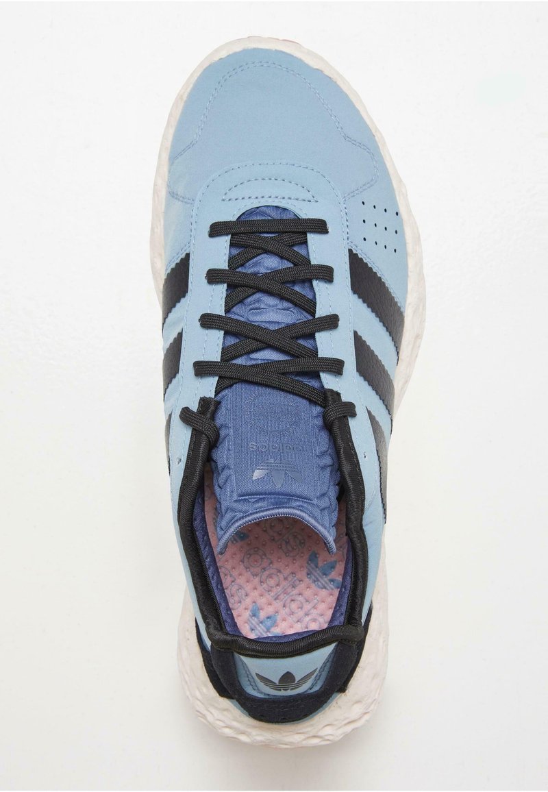 Lichtblauwe sneaker met zwarte strepen, zwarte veters en een textuur roze binnenzool. Heeft een afgeronde witte zool en gestikte details.