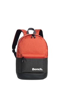 Rode stoffen rugzak met een zwarte onderkant en grijze accenten. Voorzien van verstelbare schouderbanden en een voorvak met een rits. "Bench." logo duidelijk zichtbaar.