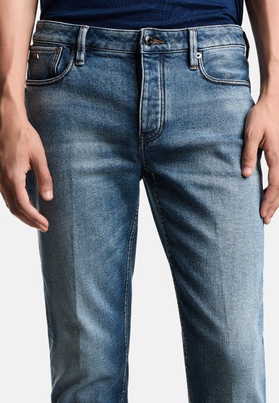 Jeans in denim blu chiaro con un classico design a cinque tasche. Presentano una chiusura con bottone e una leggera scoloritura su tutto il tessuto.