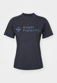 Kortermet svart skjorte, laget av glatt stoff, med teksten "Sweet Protection" i en kontrasterende mørk blå farge på forsiden.