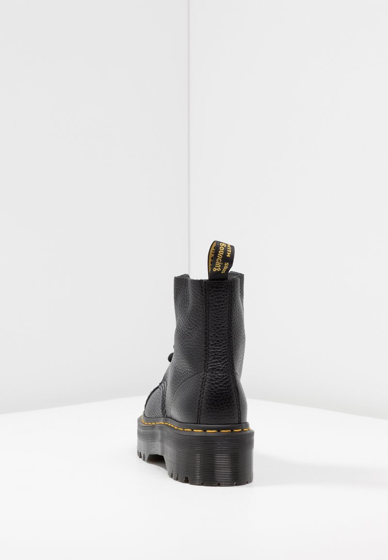 Black leather ankle boot with a textured finish, chunky sole, and yellow stitching. Features a pull tab at the heel for easy wear.