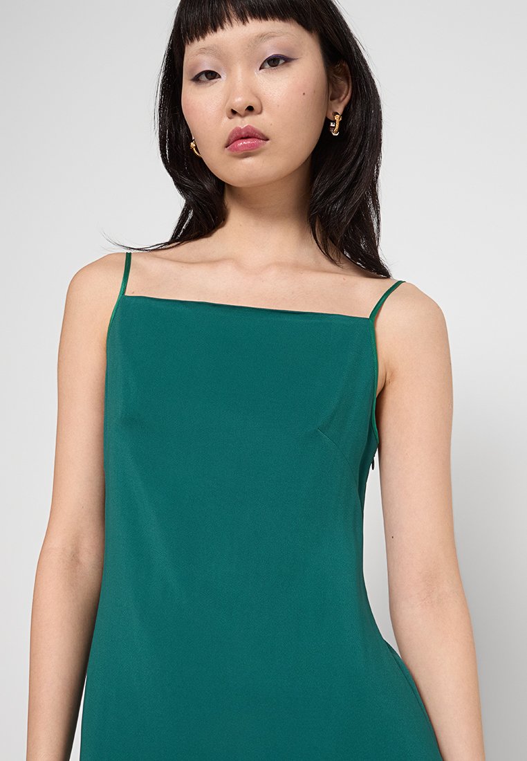 Türkises Slipkleid mit dünnen Trägern und geradem Ausschnitt. Glatte Textur, A-Linie-Schnitt, minimalistisches Design und keine sichtbaren Muster oder Beschläge.