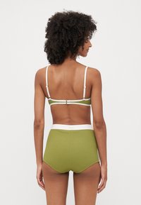 Olivenfarget ribbet bikini-sett med hvite detaljer. Toppen har justerbare stropper og spenne. Høyt midje-bunn gir full dekning.