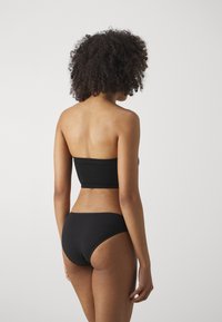 Svart, sömlös bandeau-topp i kombination med matchande bikiniunderdelar, minimalistisk design, mjuk textur och medelhög täckning.