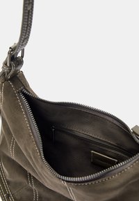 Dark brown suede bag with white stitching, zip closure, and an interior pocket. Features a detachable leather strap.