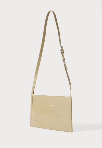 Μπεζ ορθογώνια τσάντα ώμου με ρυθμιζόμενο λουρί και μίνιμαλ ραφές, εμφανίζεται σε απλό φωτεινό φόντο.