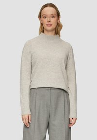 Hellgrauer Strickpullover mit hohem Kragen, langen Ärmeln und gerippten Bündchen. Kombiniert mit strukturierten grauen Hosen, die einen geschichteten Look kreieren.