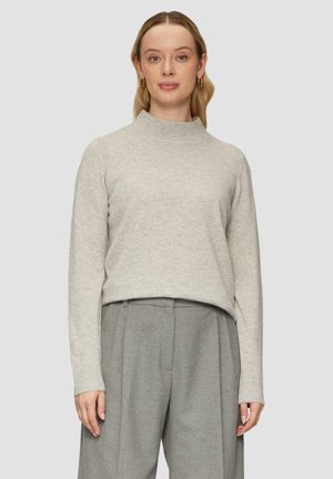 Light gray knitted sweater with a high neckline, long sleeves, and ribbed cuffs. Paired with textured gray trousers, creating a layered look.