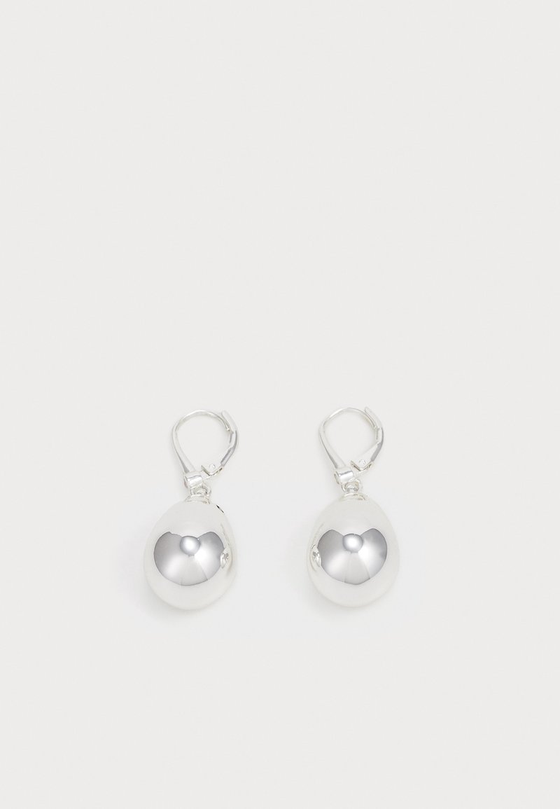 Paire de boucles d'oreilles pendantes rondes en argent brillant avec fermoirs à levier sur fond blanc uni.