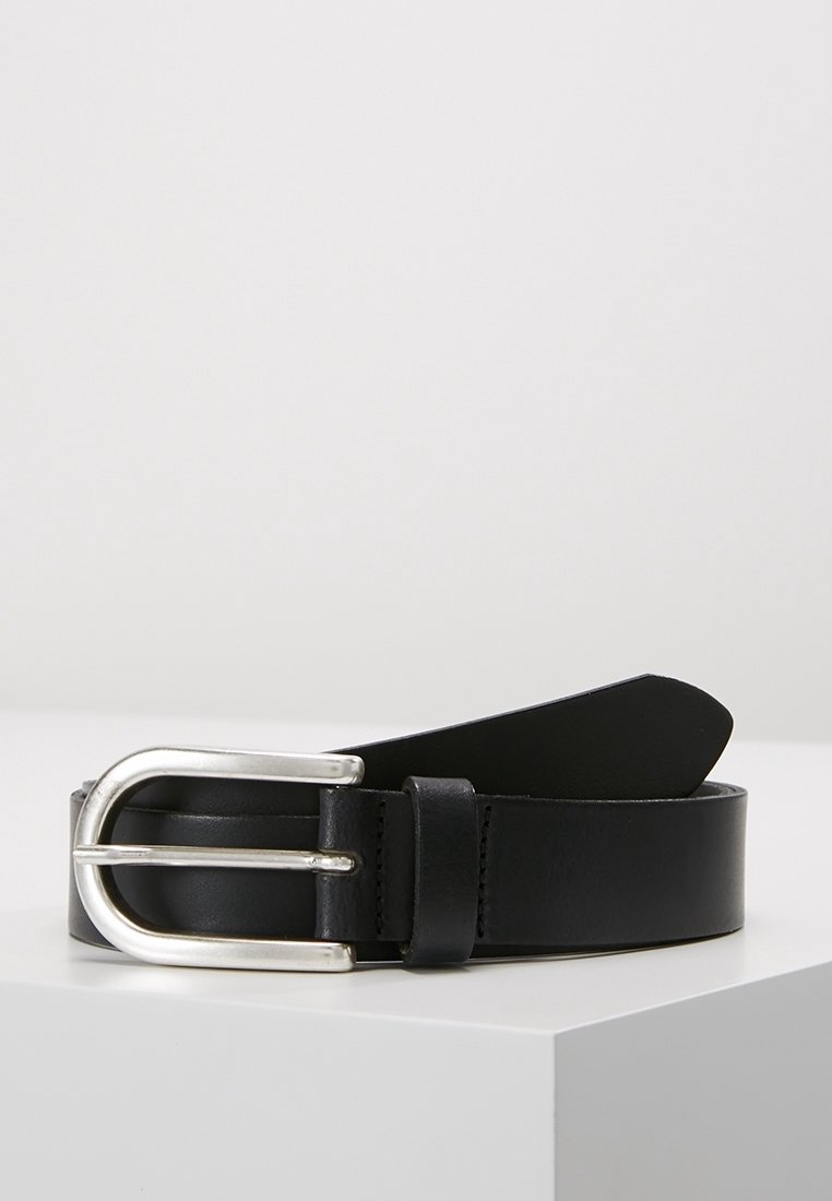 Ceinture en cuir noir avec une boucle métallique argentée arrondie de forme rectangulaire, posée sur une surface blanche.