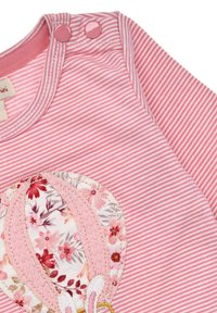 Gestreifter rosa Stoff mit einem Design von Heißluftballons, verziert mit floralen Akzenten und Stickerei. Zwei rosa Druckknöpfe an der Schulter zur Befestigung.