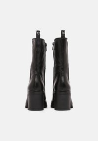 Czarne skórzane botki za kostkę z blokowym obcasem, zamek błyskawiczny oraz pętelkowymi uchwytami u góry. Gładka faktura z minimalnym zdobieniem.