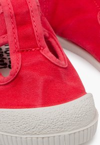 Scarpe rosse in tela con suola in gomma bianca testurizzata e design senza lacci, dotate di dettagli cuciti e aperture laterali.