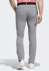 Pantalones slim-fit grises, hechos de una tela suave, con dos bolsillos traseros y una cinturilla negra, combinados con zapatillas blancas.