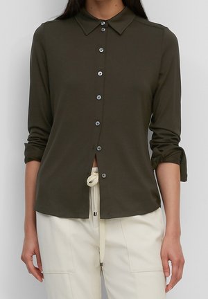 Camicia verde oliva con bottoni, colletto, maniche lunghe risvoltate ai polsini, con bottoni neri e orlo anteriore leggermente arricciato.