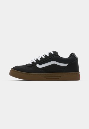 Black sneaker with white side stripe, textured rubber sole, and padded collar. Features white laces and red accent on the heel.