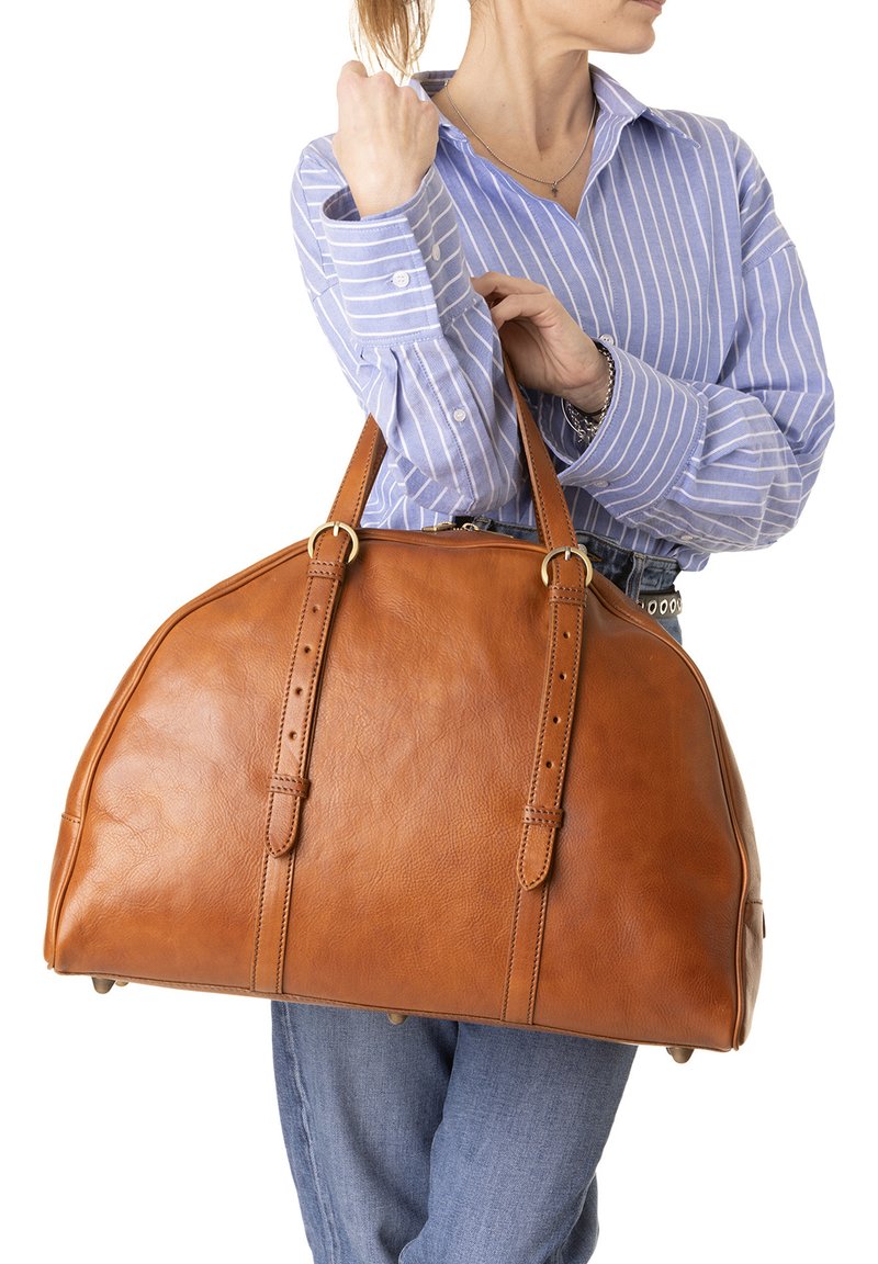 Borsa da viaggio in pelle marrone con forma strutturata, due manici a tracolla in contrasto, accessori in ottone e superficie liscia.