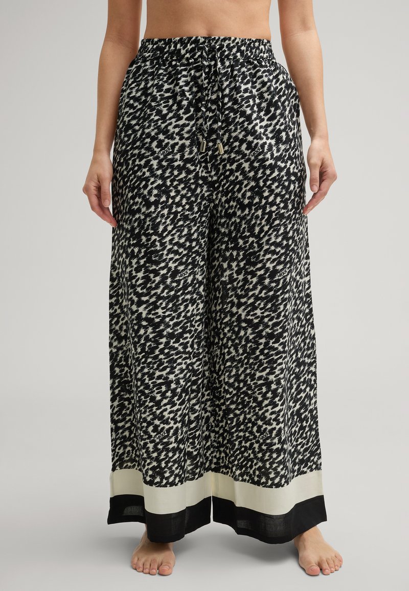 Spodnie szerokie w czarno-białym abstrakcyjnym wzorze, z elastycznym paskiem w talii i sznurkiem do regulacji, oraz kontrastującym czarnym wykończeniem na dole.