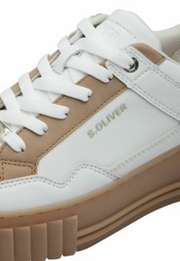 Sneaker bianco e beige con chiusura a lacci, tomaia in pelle texture, dettaglio logo metallico e suola in gomma spessa con accenti scanalati.