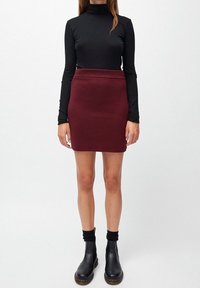 Svart långärmad polotröja, burgundyröd figurnära kjol och svarta anklarstövlar. Slät tyg med ribbad midja och stövladetaljer.