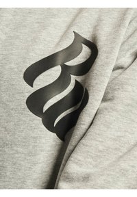 Den grå sweatshirtstof har et stort sort logo designet på forsiden, med en let struktureret og blød overflade.