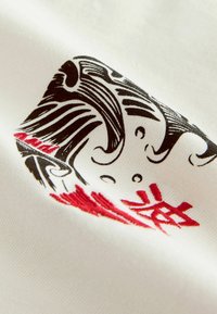 Biely textil s podrobným čierno-červeným grafickým dizajnom, ktorý obsahuje štýlové vlny a postavy. Jemná textúra a hladký povrch.