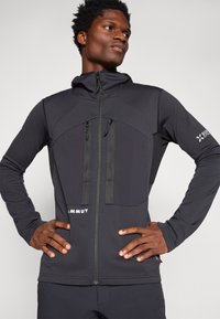 Black zip-up jacket featuring a fitted design with two front pockets, textured shoulders, and elbow panels for added durability.