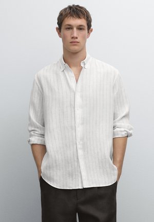 Witte button-up shirt met verticale grijze strepen, opgerolde mouwen en een zachte textuur, gecombineerd met donkere broeken. Eenvoudig en op maat gemaakt design.