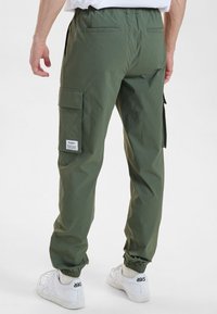 Grønne cargo-bukser med elastisk talje, der har sidelommer og en baglomme. Lavet af letvægtsstof med tætsiddende manchetter.