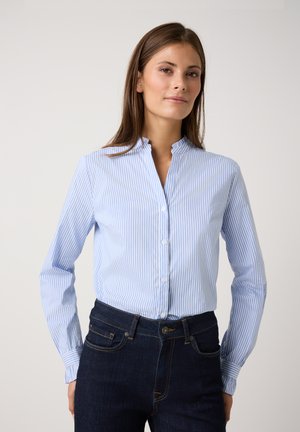 Hellblau und weiß gestreiftes Button-Down-Hemd mit Stehkragen und langen Ärmeln, kombiniert mit dunkelblauen Jeans. Weiche Stofftextur.