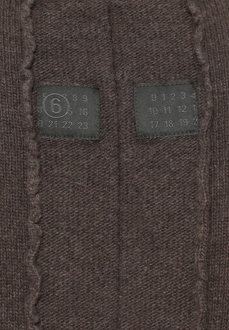Close-up of dark brown knitted fabric with two black labels showing embossed numbers and a circled number 6 on the left label.