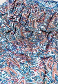 Tissu à motif paisley coloré en bleu, orange et blanc, avec des détails froncés et une texture douce et légère.
