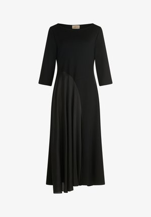Robe noire avec un corsage ajusté, des manches trois-quarts et un design de jupe asymétrique fluide avec des textures superposées. Tissu lisse.