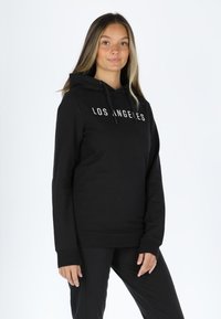 Black hoodie with drawstrings, featuring "LOS ANGELES" in white print on the front. Soft fabric, relaxed fit, and ribbed cuffs.