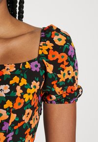 Abito nero floreale con maniche a palloncino corte, scollo a quadrato e un motivo floreale multicolore in tonalità di arancione, viola e giallo.