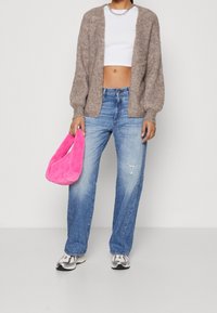 Brązowy puszysty kardigan, biały crop top, jasnoniebieskie luźne dżinsy, różowa puszysta torebka i szare sneakersy z czarnymi akcentami.