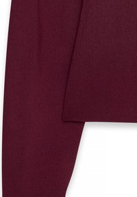 Lähikuva pitkähihaisesta burgundy-neulepaidasta, jossa on teksturoitu kangas ja ribbireunat hihassa.
