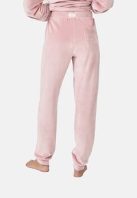 Jogging en velours rose avec une coupe décontractée, dotée d'une taille élastique et d'une poche arrière. Texture douce et chevilles resserrées.