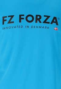 Turkos sport T-shirt med "FZ FORZA" i fet svart text och "INNOVATED IN DENMARK" text, med en liten dansk flagga som symbol.