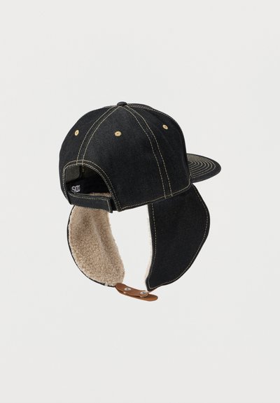 Musthave musta teksast kapuutsiga, beezist fliisist kõrva klapid, kollased õmblused ning reguleeritav pruun nahk rihm tagaküljel.
