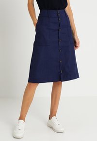 Navy denim midi skirt with a straight cut, featuring a front button closure, two pockets, and a subtle textured finish.