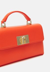 Oranžová kožená kabelka se strukturovaným designem, s horní rukojetí, zlatým zapínáním a texturovaným povrchem.