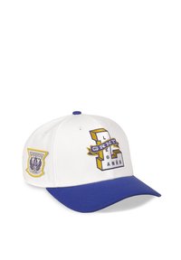 Gorra de béisbol blanca con visera azul. Presenta un logo y una insignia bordados en amarillo y azul. El material parece tener una textura con una forma estructurada.