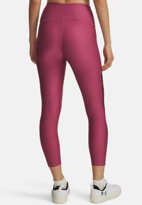 Fitted, high-waisted leggings in dark pink, featuring a smooth texture and a side black floral pattern, paired with white athletic shoes.