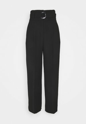 Pantalon noir taille haute avec passants de ceinture, une large ceinture dotée d'une boucle ronde argentée et un pli marqué à l'avant.